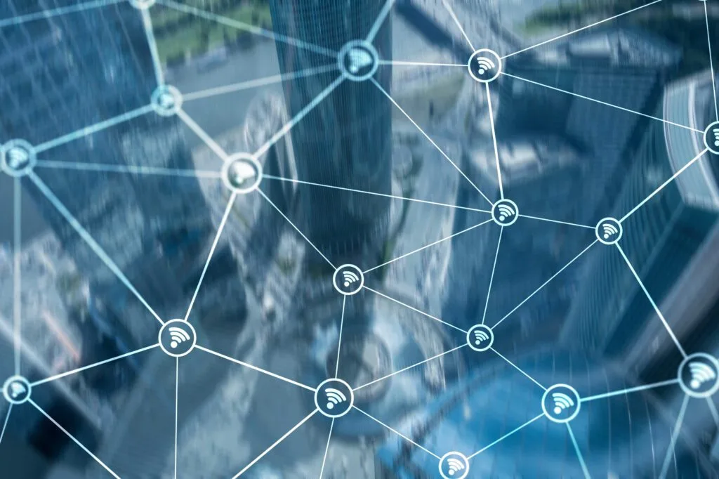 Conceptual image of a cityscape overlaid with a network visualization featuring interconnected nodes with Wi-Fi symbols, representing connectivity or communication networks.
