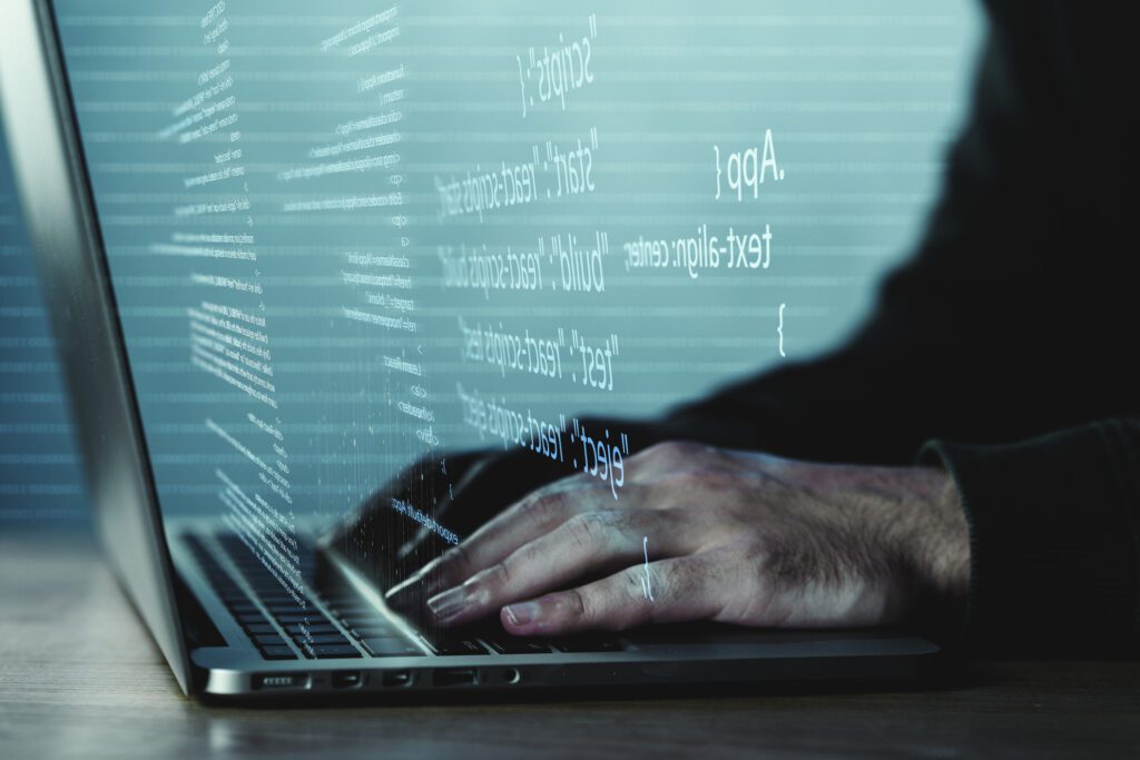 A close-up of a person's hands typing on a laptop keyboard with lines of computer code projected in the air, giving a high-tech, programming-focused aesthetic.